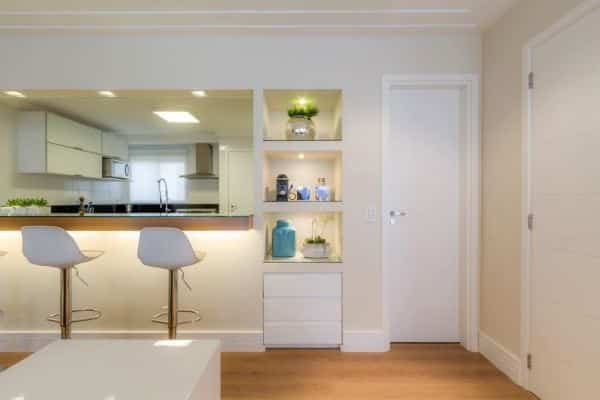 Parede de gesso com nichos que serve como divisória para sala e cozinha.