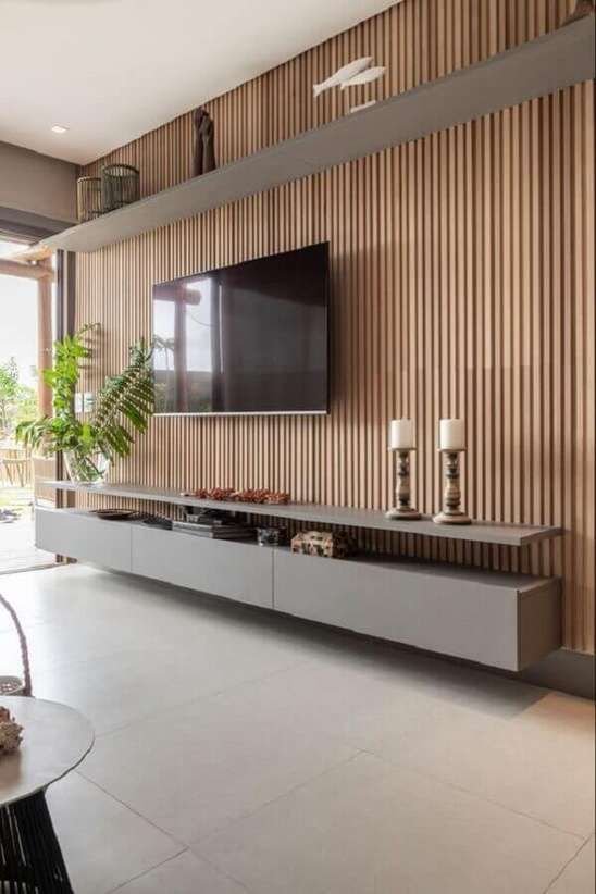 5. Esse tipo de elemento consiste na organização de ripas de madeira naturais que são organizadas lado a lado para compor toda a parede e formar uma painel para sua tv.