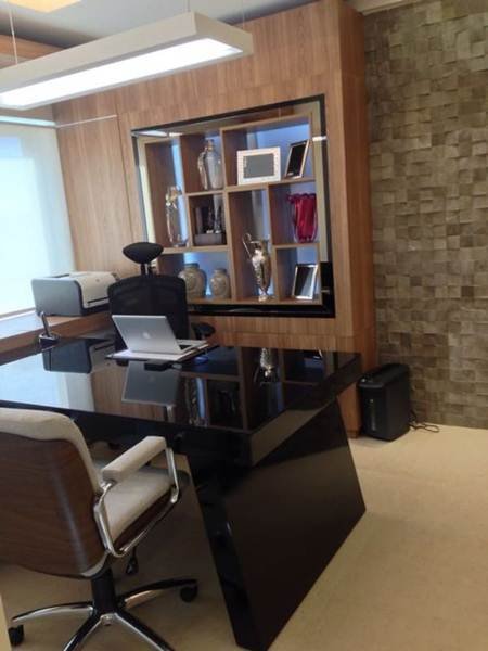 Um escritório estiloso com mesa preta, parede de pedras e estante de madeira embutida.